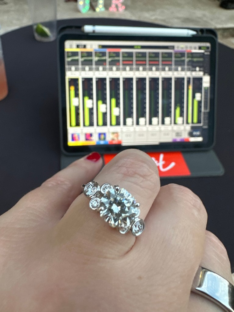 Wendi showing her engagement ring with a digital sound mixing board in the background after Dan proposed.