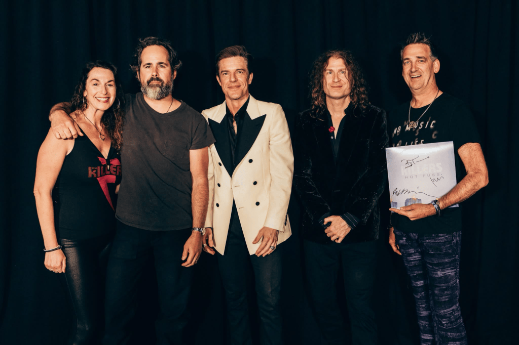 Wendi and Dan meeting The Killers, with Dan holding the album he had signed by the band.