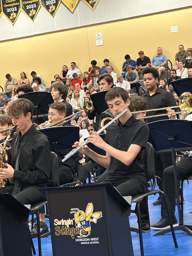 AJ playing flute with his school concert band during a performance.