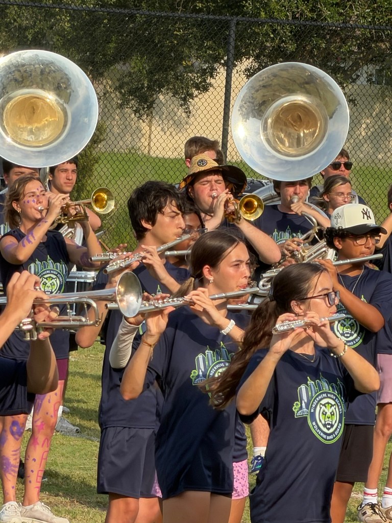 AJ playing flute outdoors with his high school marching band.