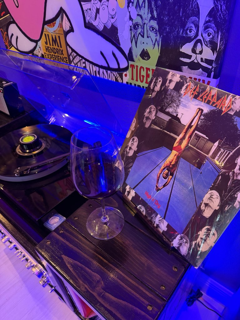 A vinyl record playing on the turntable beside a glass of wine and a Def Leppard album in Wendi and Dan’s music room.