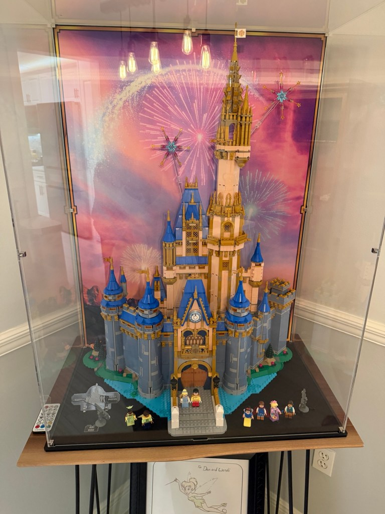 Large LEGO Cinderella Castle displayed in a custom case with a colorful fireworks backdrop and Disney character minifigures.
