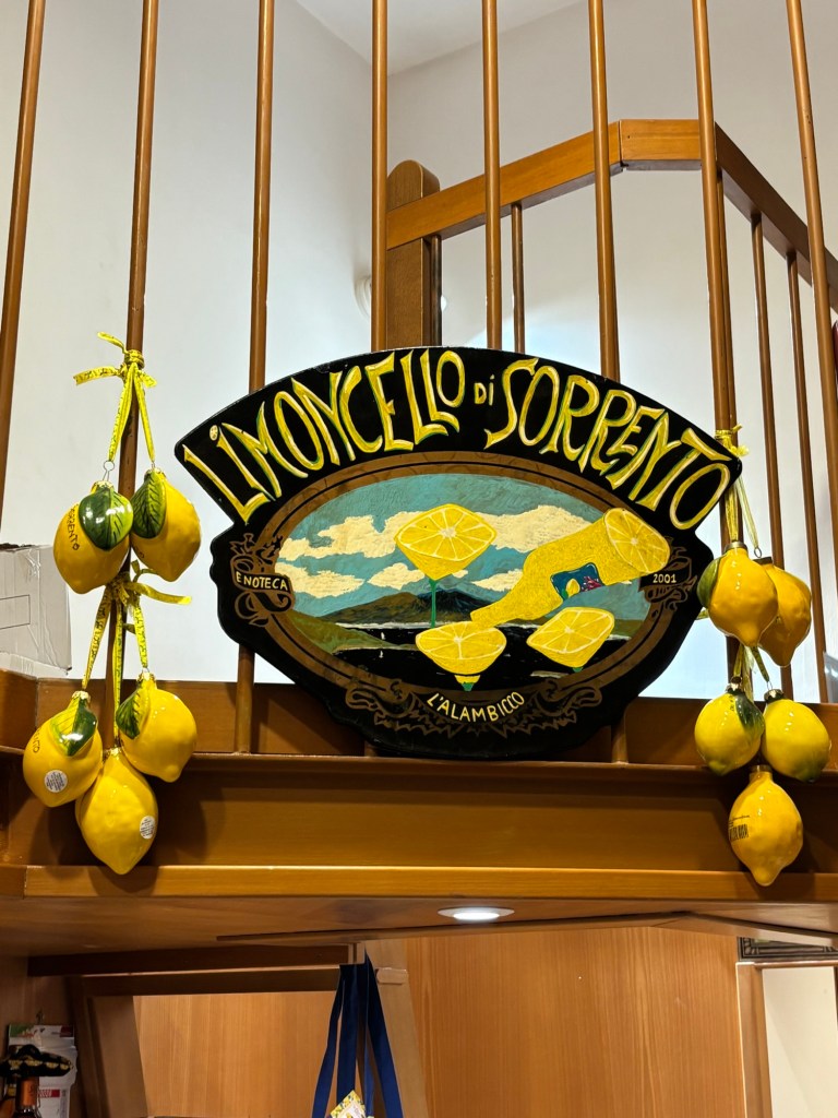 A painted “Limoncello di Sorrento” sign surrounded by hanging yellow ceramic lemons.