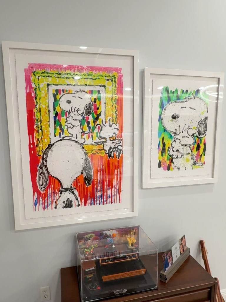 Two colorful framed Tom Everhart paintings featuring Snoopy and Woodstock
