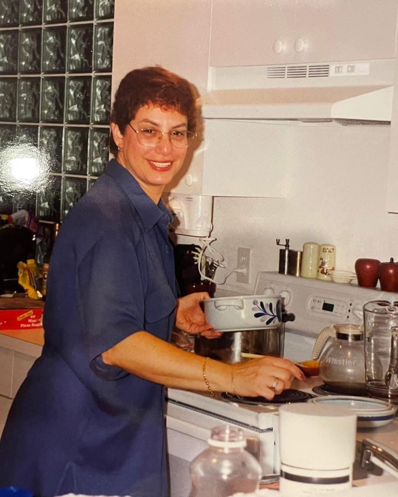 Wendi’s mom smiling while preparing a holiday meal at the stove in the family kitchen.