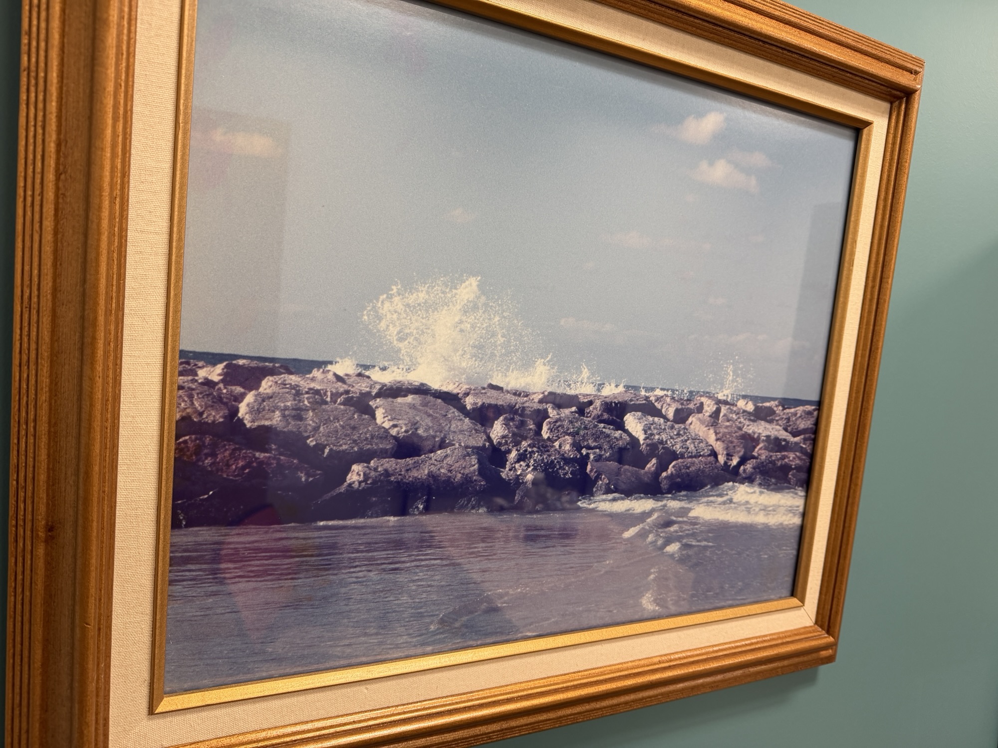 Original 1997 photograph of Mediterranean waves crashing against rocks in Tel Aviv, displayed in a wooden frame.
