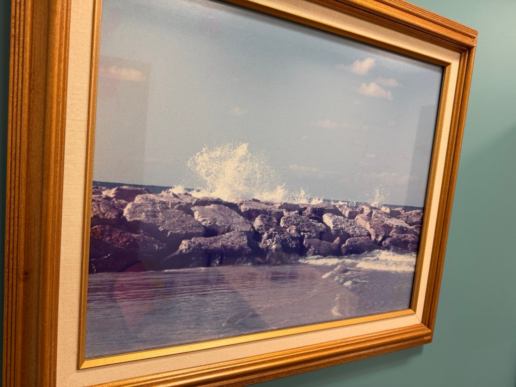 Original 1997 photograph of Mediterranean waves crashing against rocks in Tel Aviv, displayed in a wooden frame.